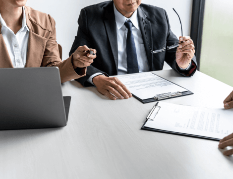 Two loan agents seated side by side in an office discussing low interest business loans.